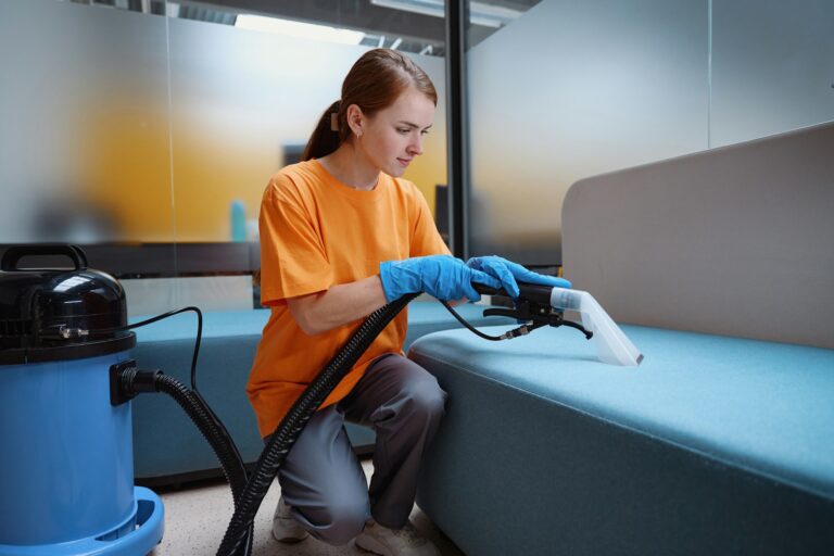 Focused cleaning service worker vacuum-cleaning the sofa