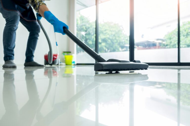 Young attractive man is cleaning vacuum commercial cleaning equipment on floor at home helping wife